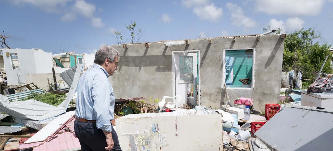 Em 2017, o secretário-geral da ONU, António Guterres, percorre um bairro destruído por seguidos furacões na cidade de Codrington, Antígua e Barbuda. Ele visitou o país para avaliar a devastação e oferecer apoio da organização. Foto: ONU/Rick Bajornas